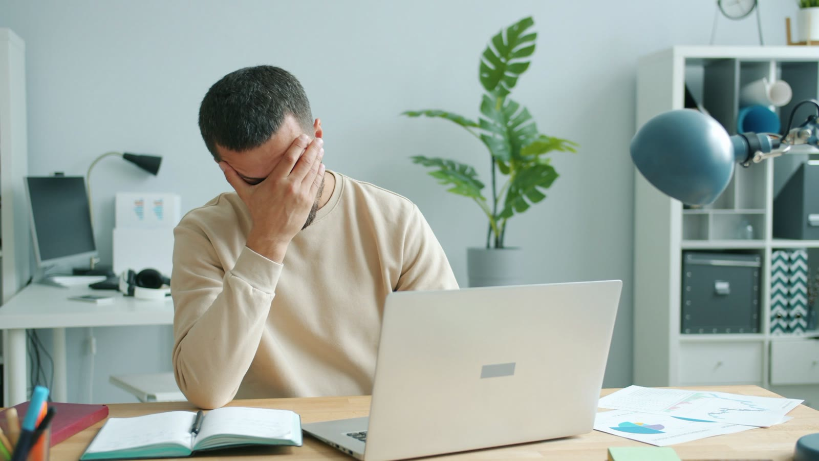 A man at his laptop with his hand over his face, stressed about a performance improvement plan