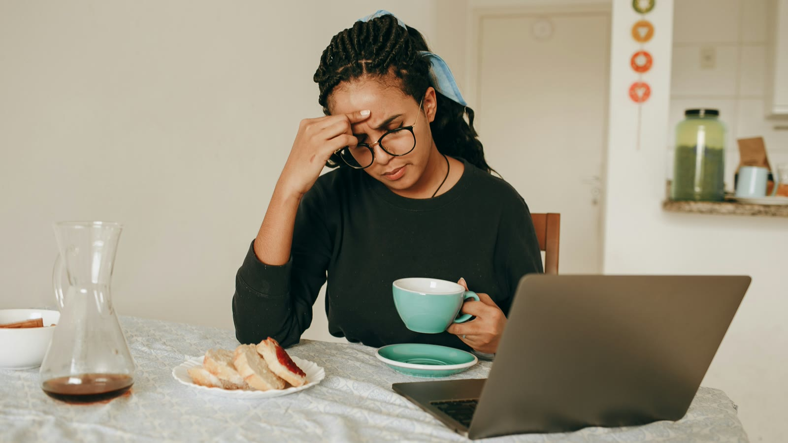 A woman at her laptop with her hand on her forehead, stressed about a performance improvement plan